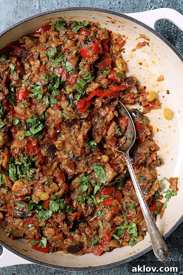 Close-up photo of Moroccan-Spiced Caponata in a white cast iron skillet, highlighting its rich texture and ingredients.