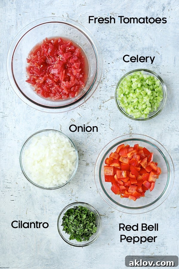 Photo of fresh ingredients for caponata in clear glass bowls, including chopped tomatoes, celery, onion, red bell pepper, and cilantro.