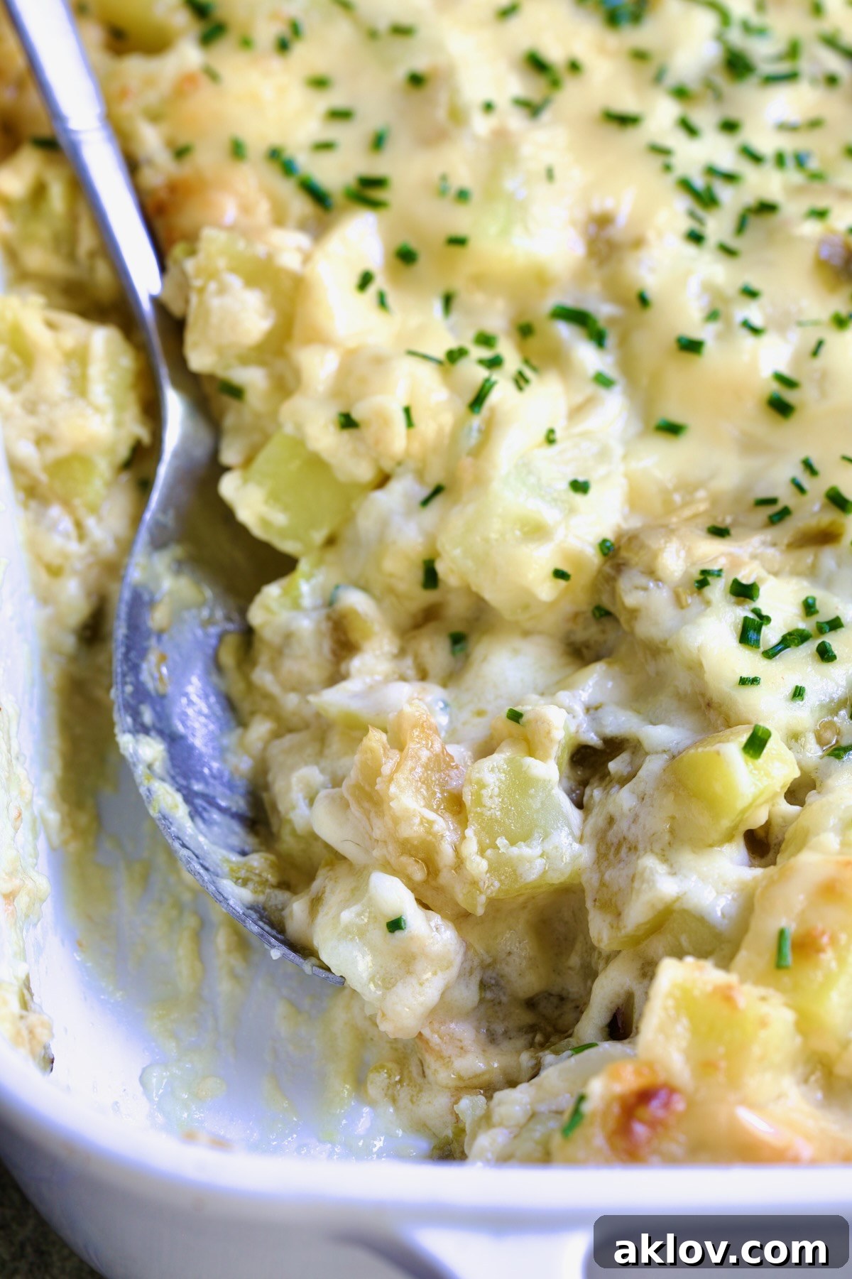 A close-up shot of a freshly scooped portion of Green Chile au Gratin Potatoes, rich with melted cheese and tender potato cubes. The golden-brown crust and creamy interior are inviting, showcasing the perfect balance of comfort and Southwestern flavor.