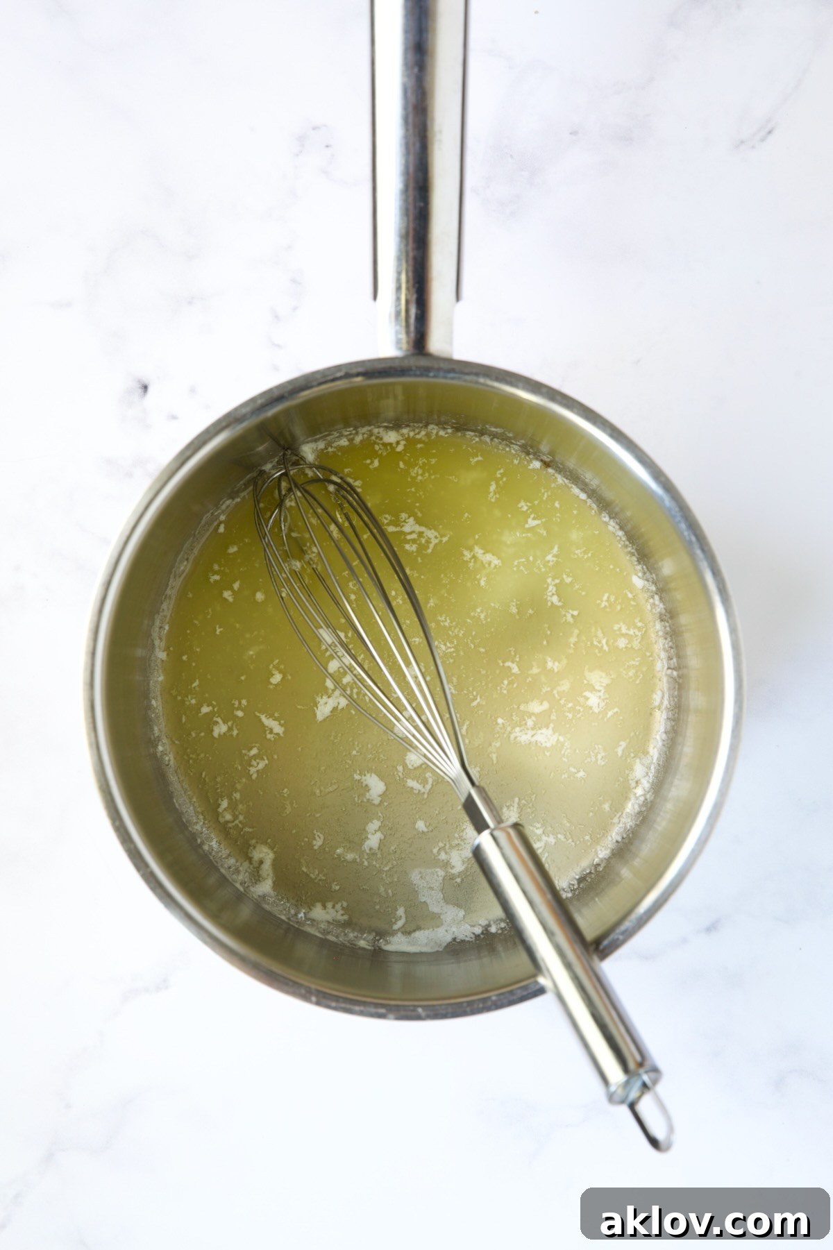 Melted butter in a stainless steel saucepan with a wire whisk, ready for the next step.
