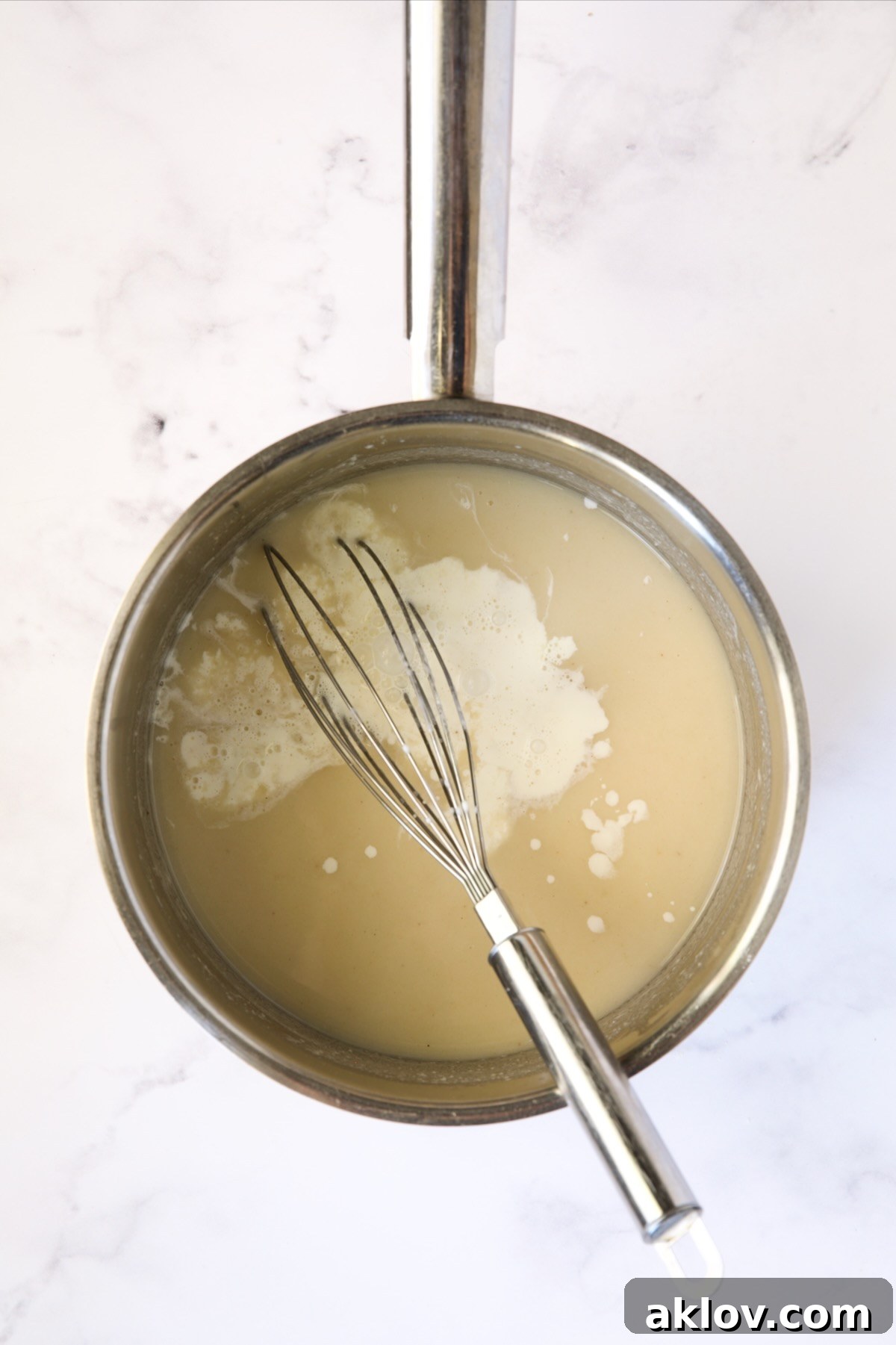 Heavy cream added to the simmering sauce in a stainless steel saucepan, enhancing its richness.