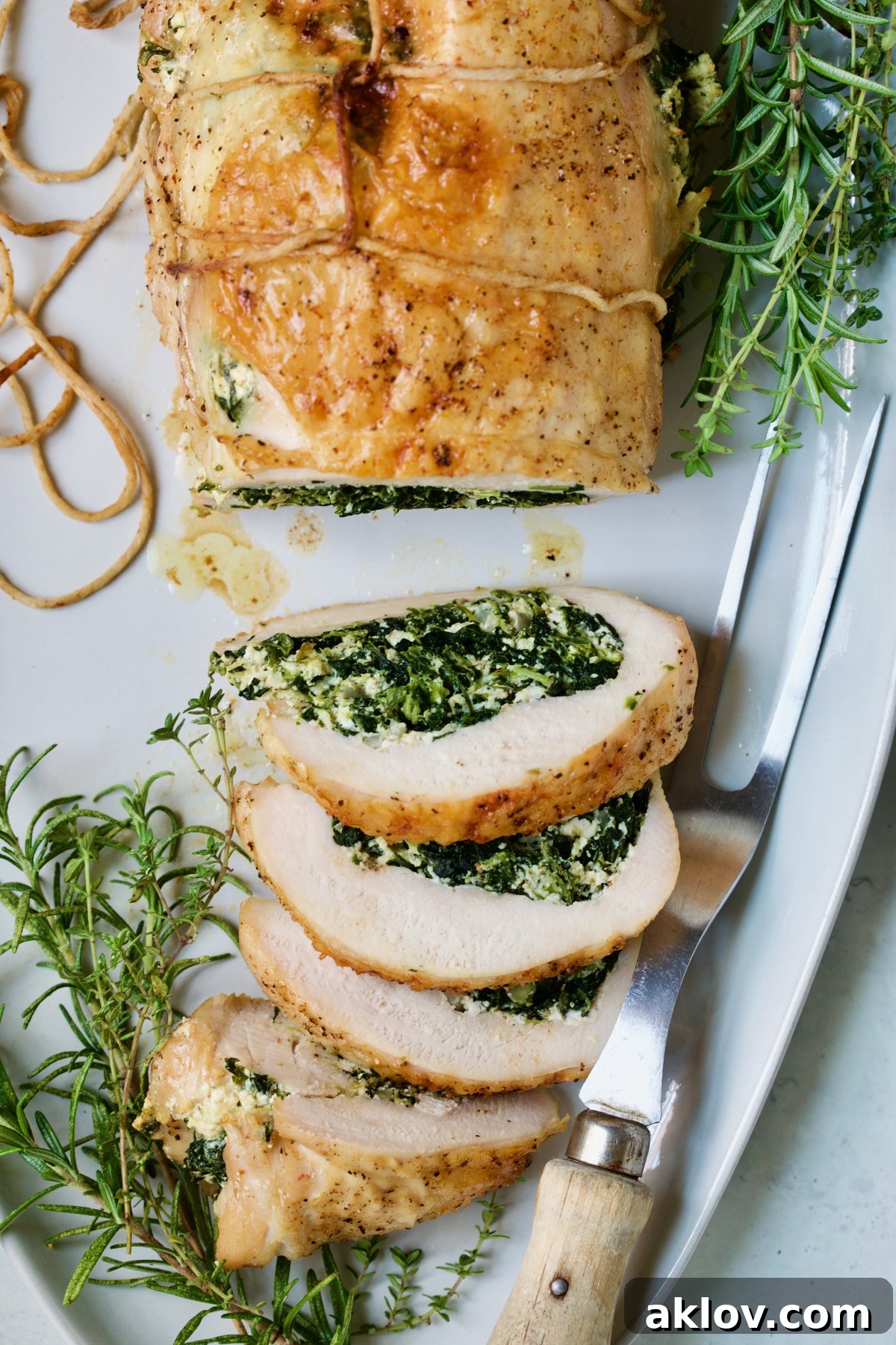 A close-up view of a sliced Spinach and Ricotta Stuffed Turkey Breast with Garlic - Herb Sauce, clearly showing the vibrant and flavorful filling, garnished with fresh herbs.