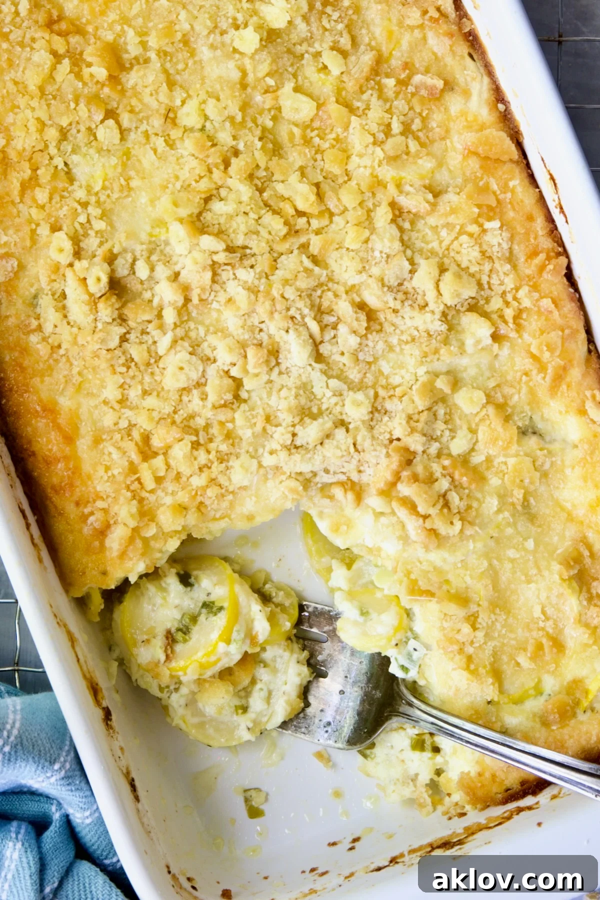 Golden Summer Squash Bake 11 A serving of Summer Squash Casserole on a fork, showcasing the tender squash and creamy filling, with the rest of the casserole in the background.