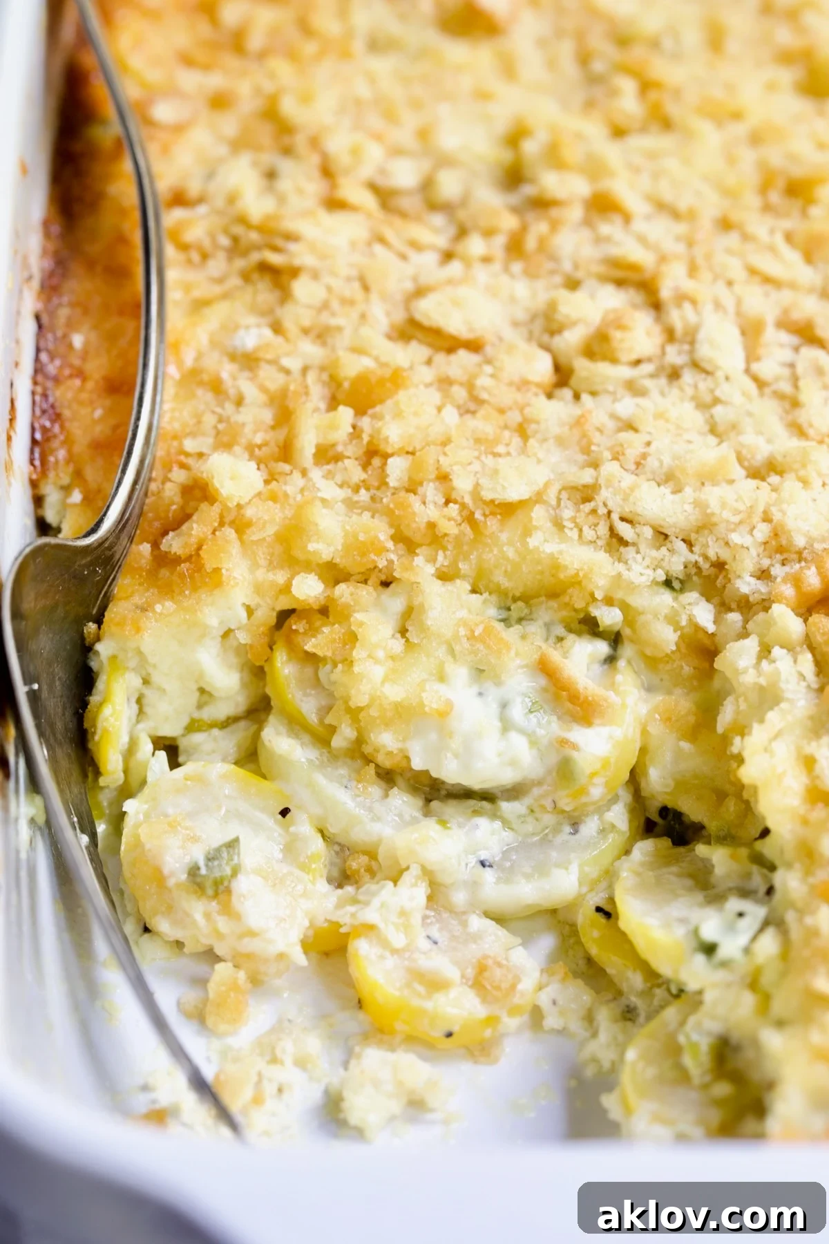 Golden Summer Squash Bake 3 A close-up shot of Southwestern Summer Squash Casserole in a white baking dish, revealing the tender squash underneath the golden-brown topping.