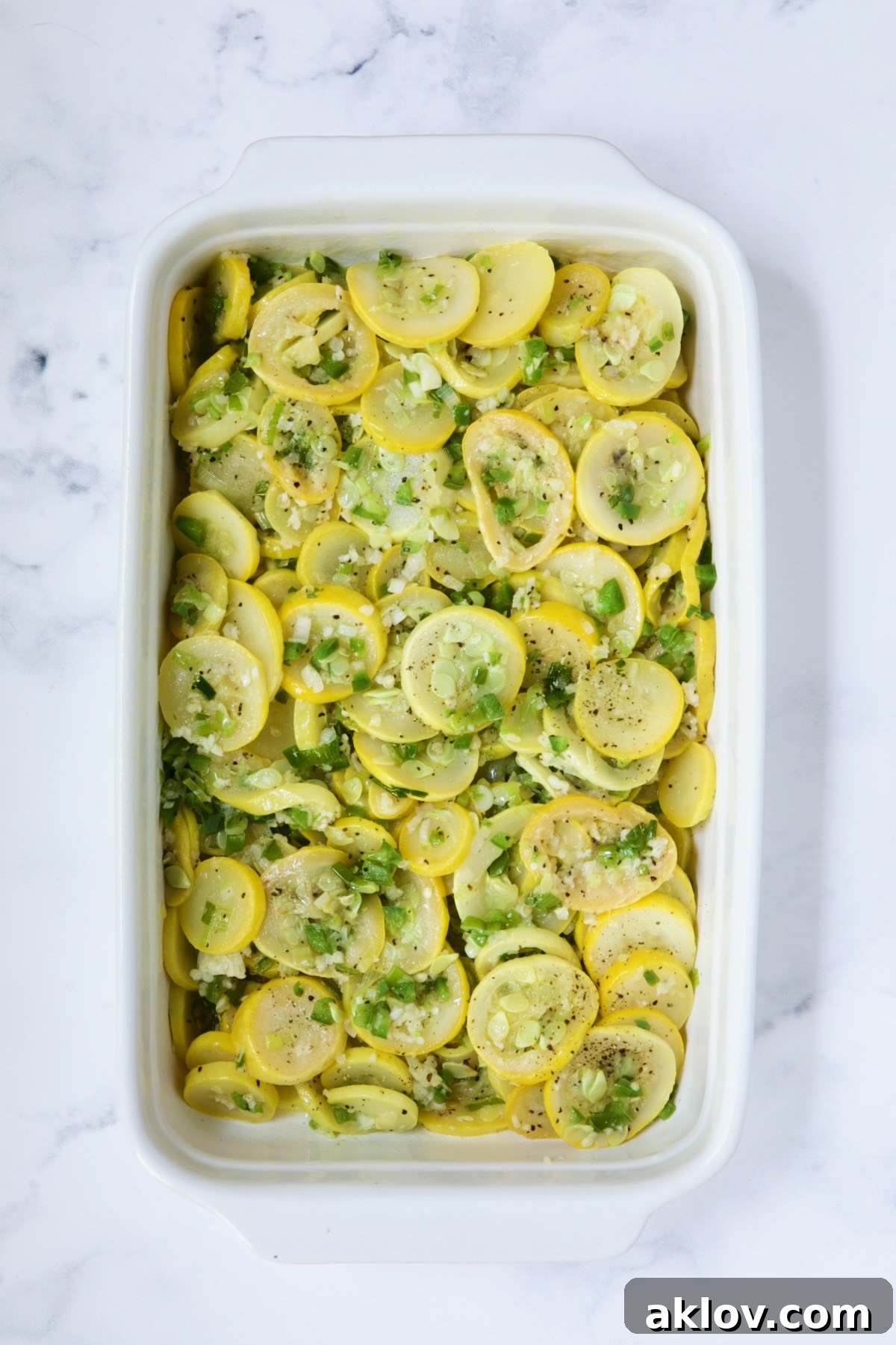 Yellow squash in white baking dish before mayonnaise and egg mixture is added.