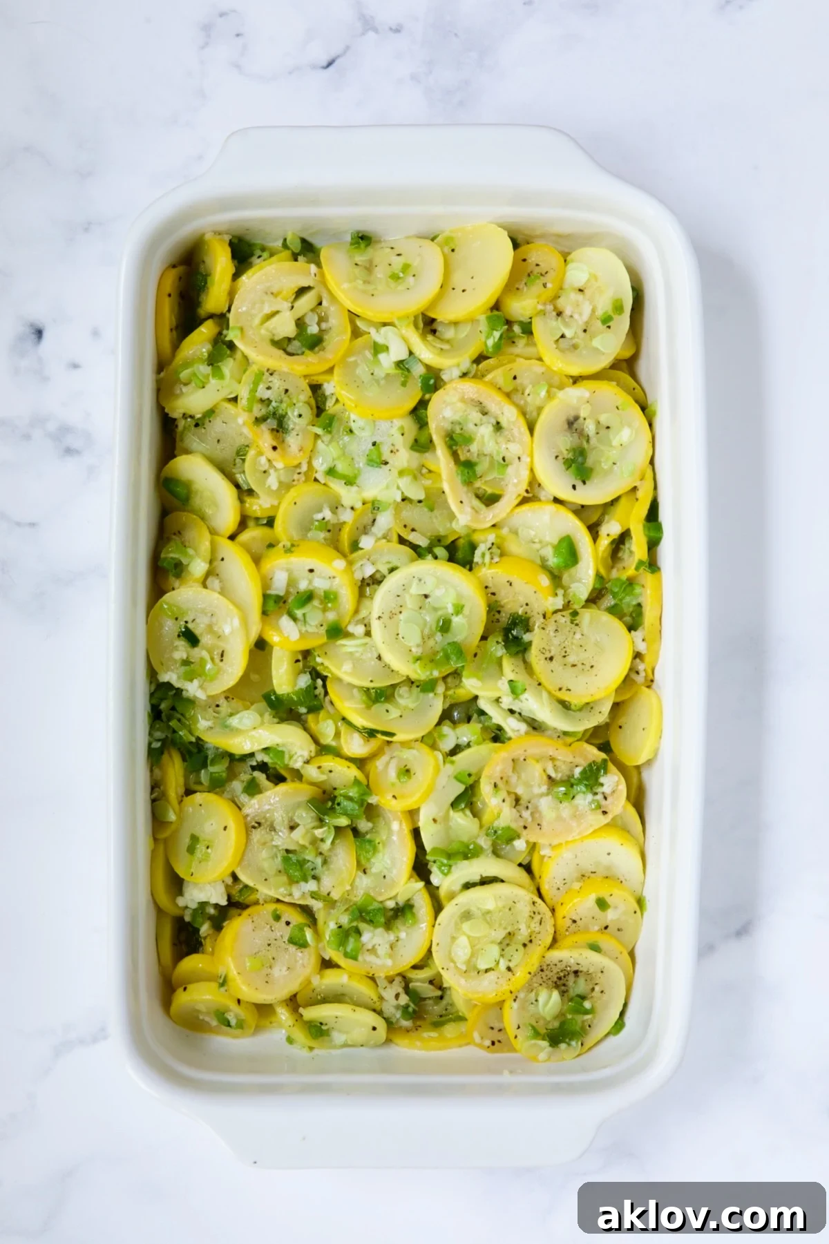 Golden Summer Squash Bake 8 Yellow squash mixture evenly spread in a white baking dish before the final creamy layer is added.