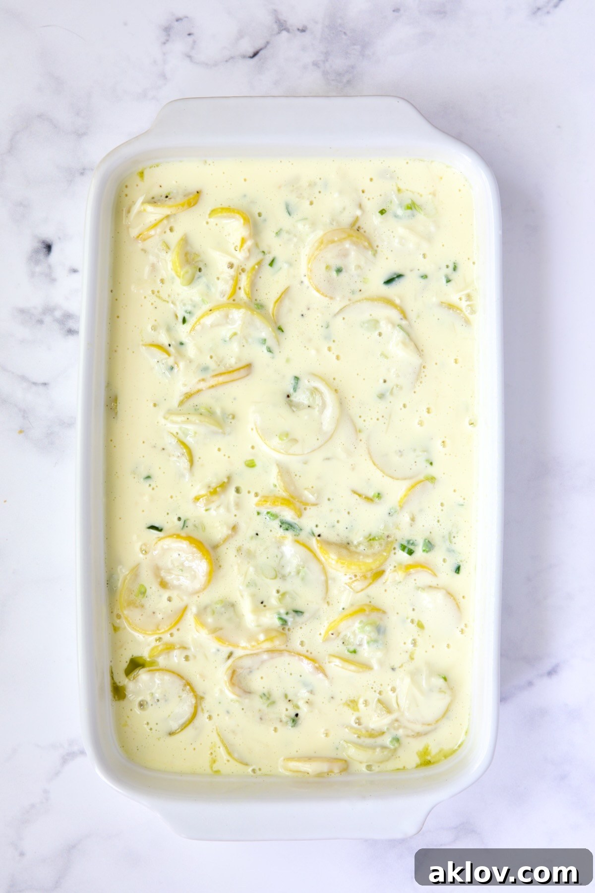 Squash casserole in white baking dish before cracker topping is added.
