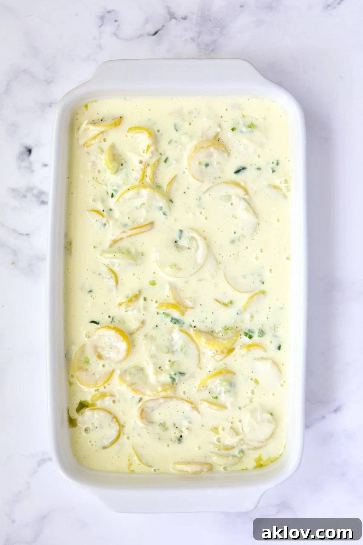 Golden Summer Squash Bake 9 Squash casserole in a white baking dish, fully assembled before the cracker topping is added.