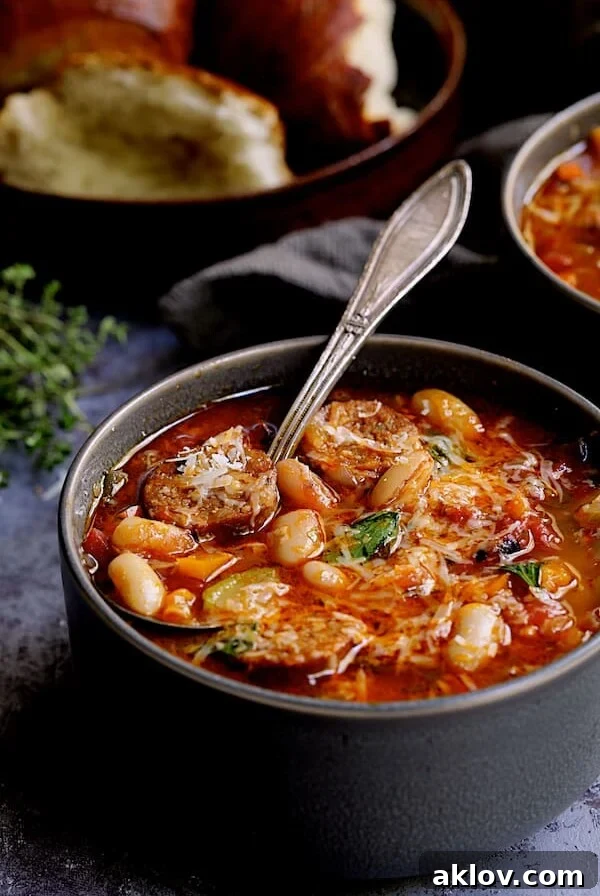 Rustic Chorizo, White Bean and Vegetable Stew 13 Chorizo White Bean and Vegetable Soup - Straight-on close-up shot of soup in gray bowl with soup spoon and bread in the background