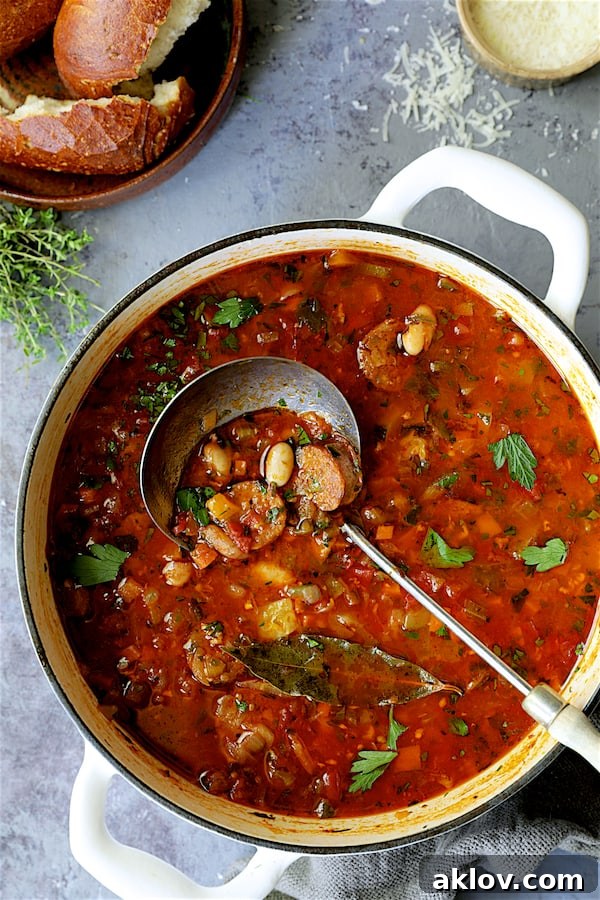 Rustic Chorizo, White Bean and Vegetable Stew 3 A large white Dutch oven filled with simmering Chorizo White Bean and Vegetable Soup, a ladle poised for serving.
