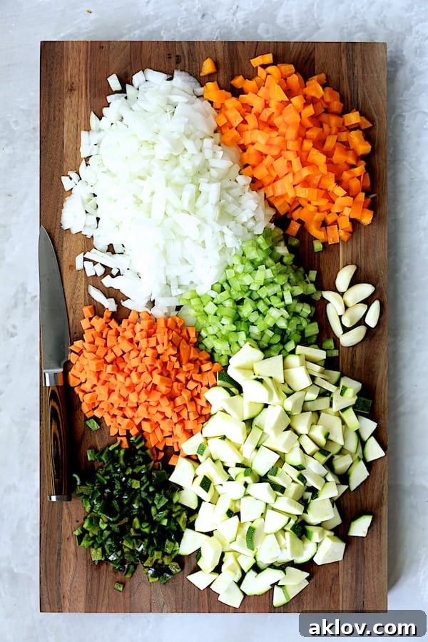 Rustic Chorizo, White Bean and Vegetable Stew 5 A colorful array of chopped vegetables, including onions, carrots, celery, bell peppers, and poblanos, neatly arranged on a dark wooden cutting board.