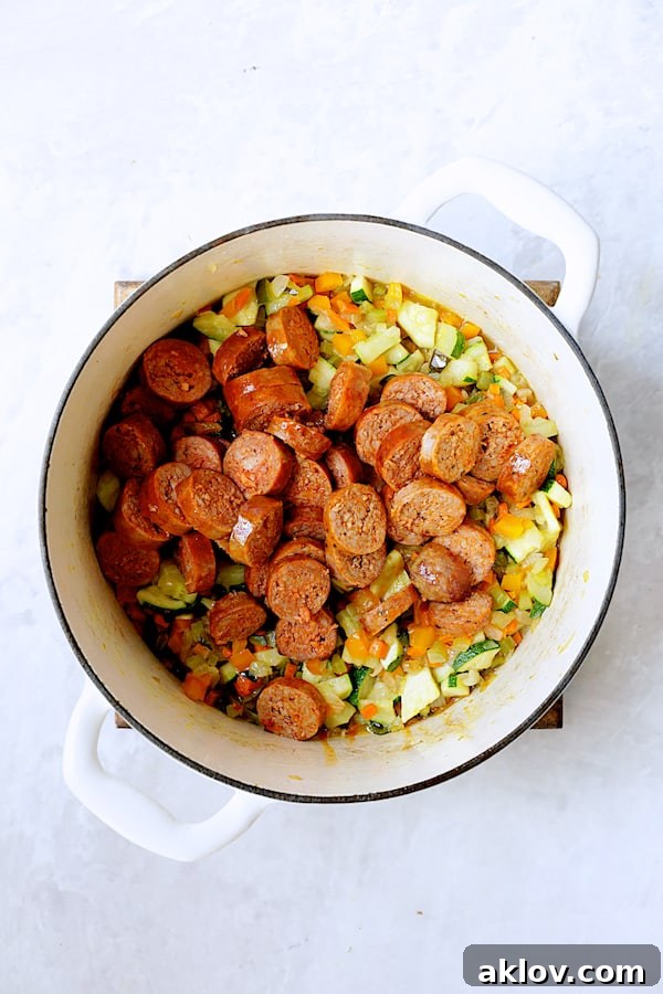 Rustic Chorizo, White Bean and Vegetable Stew 7 Sliced chorizo sausage joined by a colorful array of vegetables in a white Dutch oven, ready for the broth and beans.