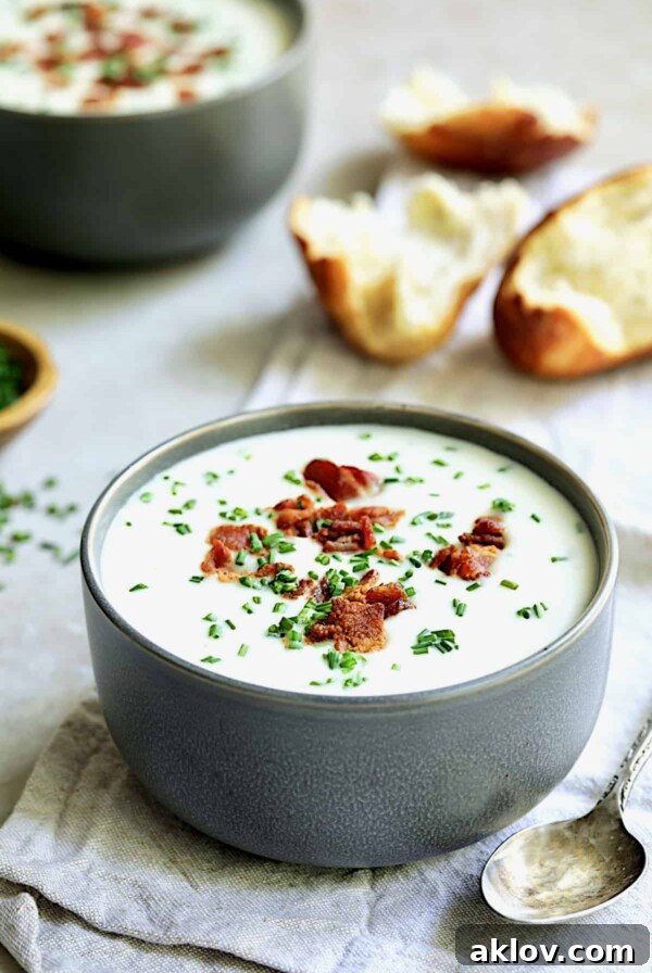 Potato and Leek Soup with White Cheddar - Straight-on shot of soup in gray bowl with broken bread in the background