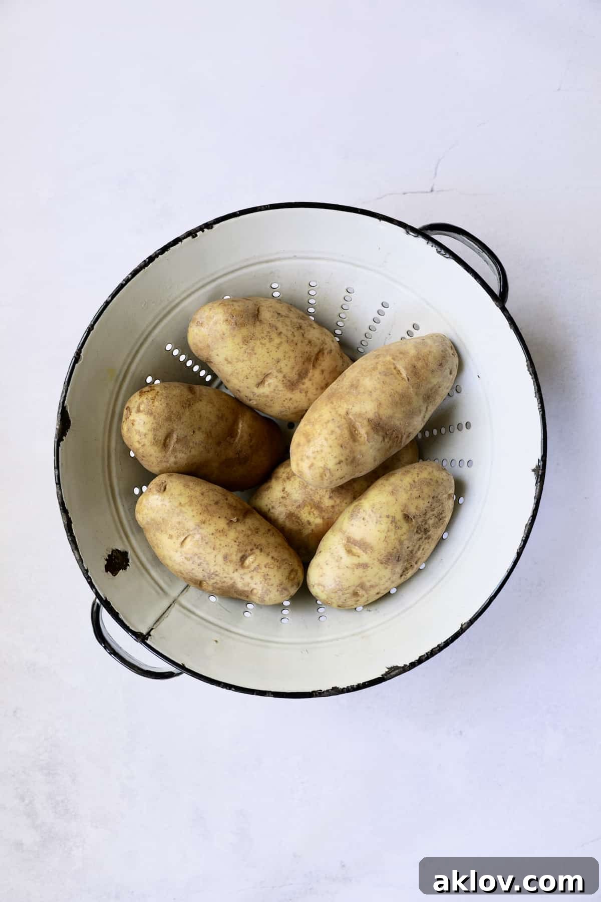 Freshly peeled Russet potatoes, uniformly cubed, resting in a white distressed colander, ready for the soup preparation.