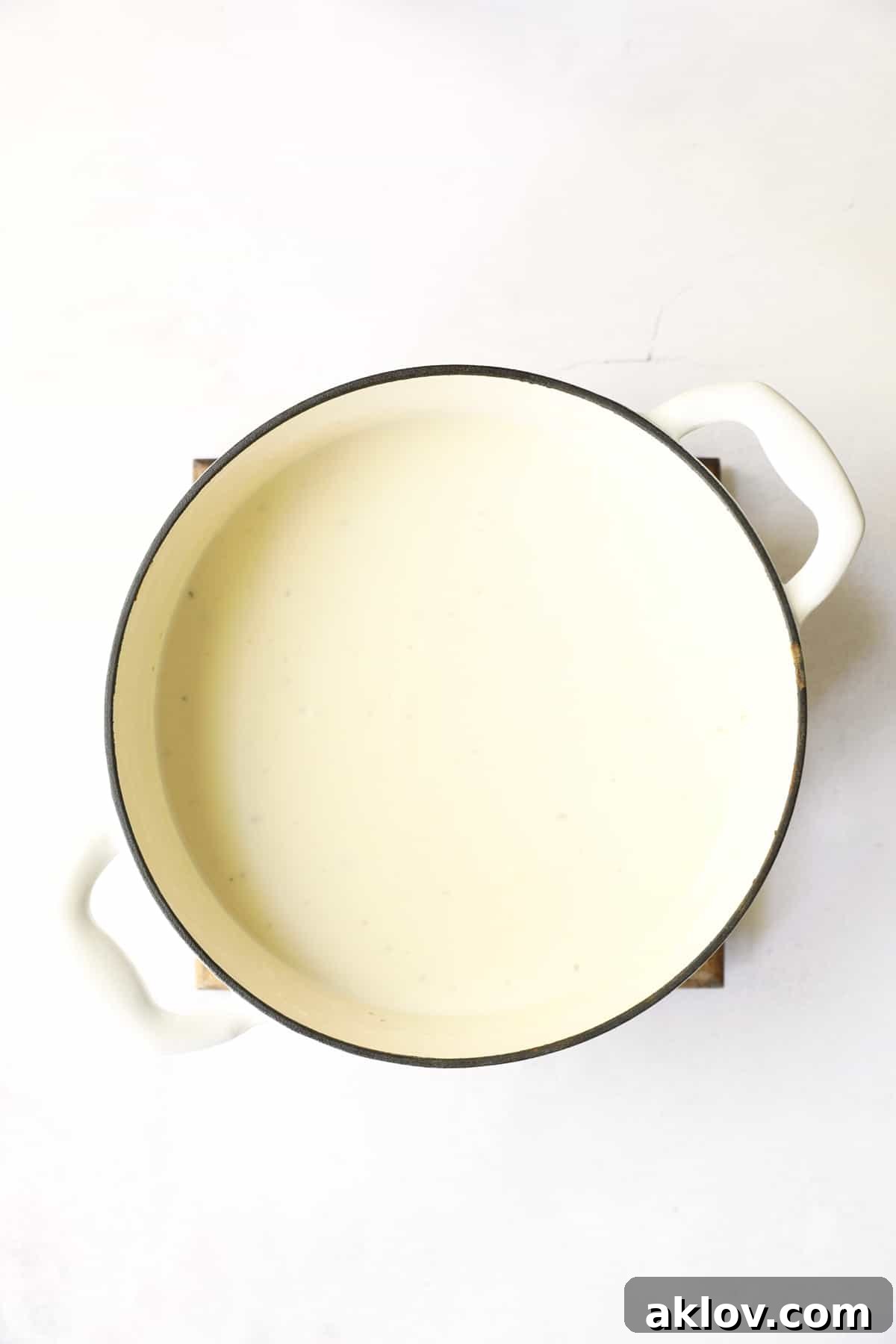 The Potato Leek Soup with White Cheddar, perfectly pureed to a smooth, creamy consistency, showcased in a white enameled Dutch oven after being blended.