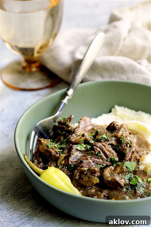 Photo of Mississippi-Style Boneless Short Ribs in green bowl with mashed potatoes garnished with parsley.
