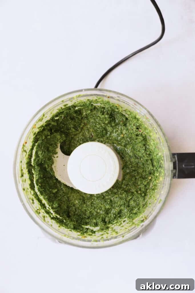 Photo of carrot top salsa verde in a food processor after being pureed to a vibrant green.