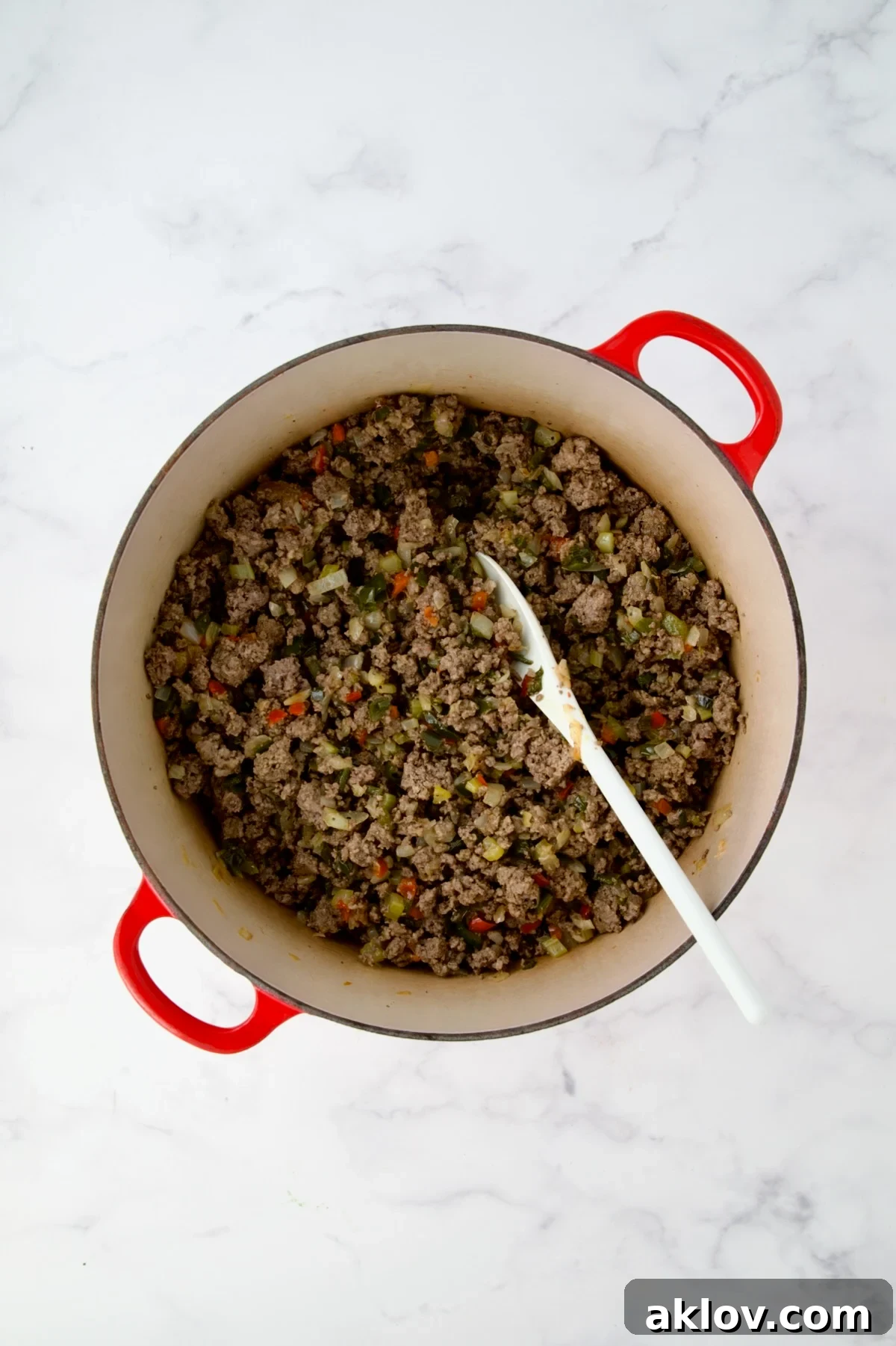 Ground beef added to cooked onions, peppers and celery in red Dutch oven.