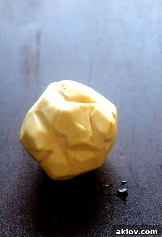 A single bulb of celery root, perfectly peeled and clean, showcasing its smooth, creamy white interior, ready for cubing.