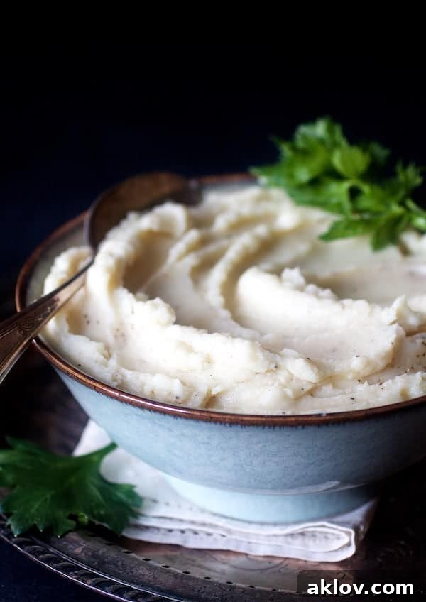 A rustic gray bowl filled with creamy Celery Root Puree, garnished with fresh celery leaves, highlighting its elegant presentation.