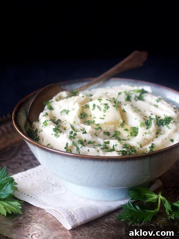 A close-up shot of creamy Celery Root Puree in a serving bowl, beautifully garnished with chopped parsley and a melting pat of butter, inviting a taste.