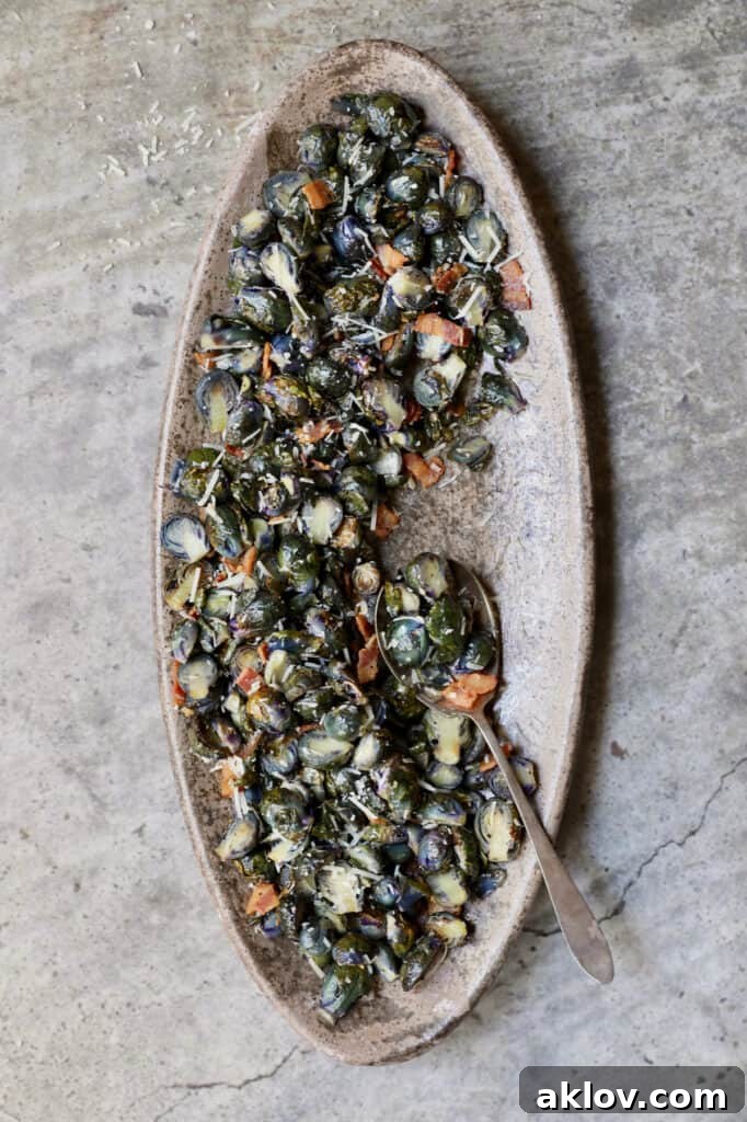 Photo of Roasted Purple Brussels Sprouts with Bacon and Parmesan on oval platter with serving spoon.