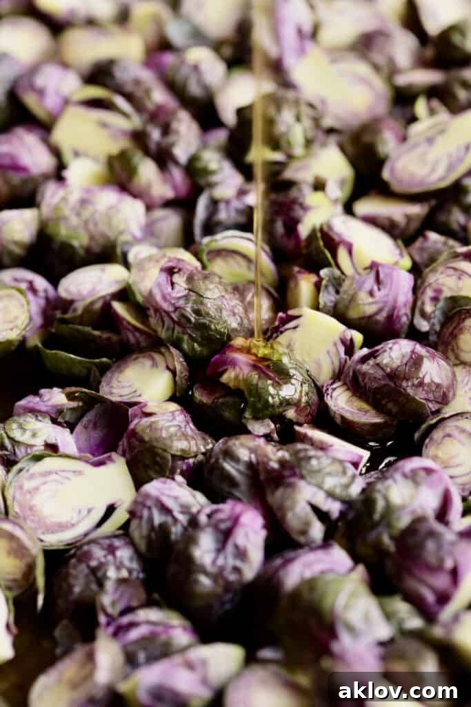 Photo of oil being drizzled over purple Brussels sprouts.
