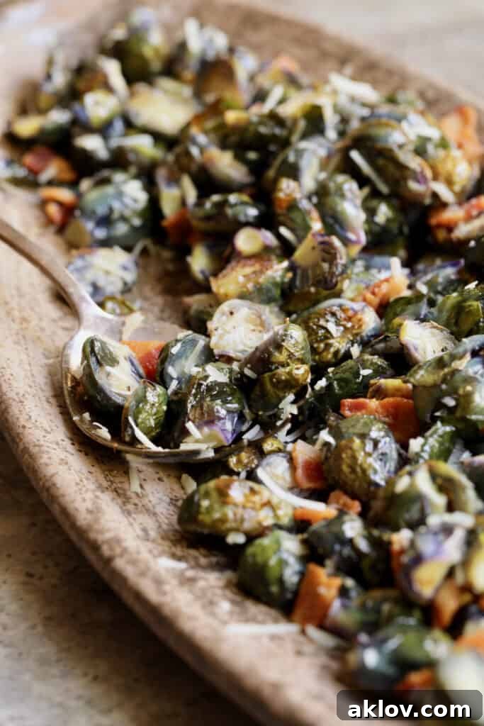 Photo of Roasted Purple Brussels Sprouts with Bacon and Parmesan on brown platter with serving spoon.