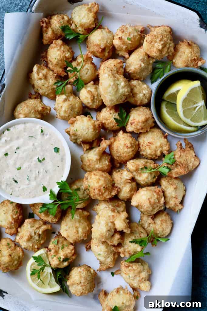 Photo of Crab and Artichoke Beignets with Jalapeno Remoulade in white pan with lemon wedges, beautifully presented.