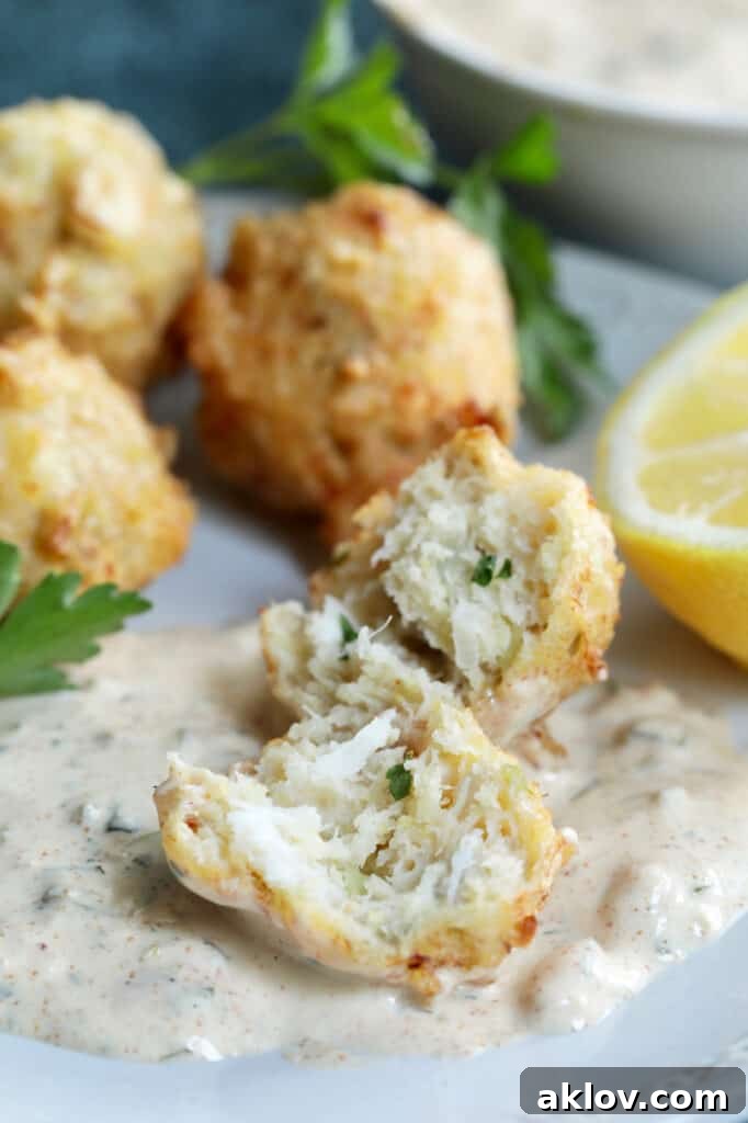 Close-up photo of a Crab and Artichoke Beignet with Jalapeno Remoulade showing interior of beignet on remoulade. A perfect fried crab fritter.