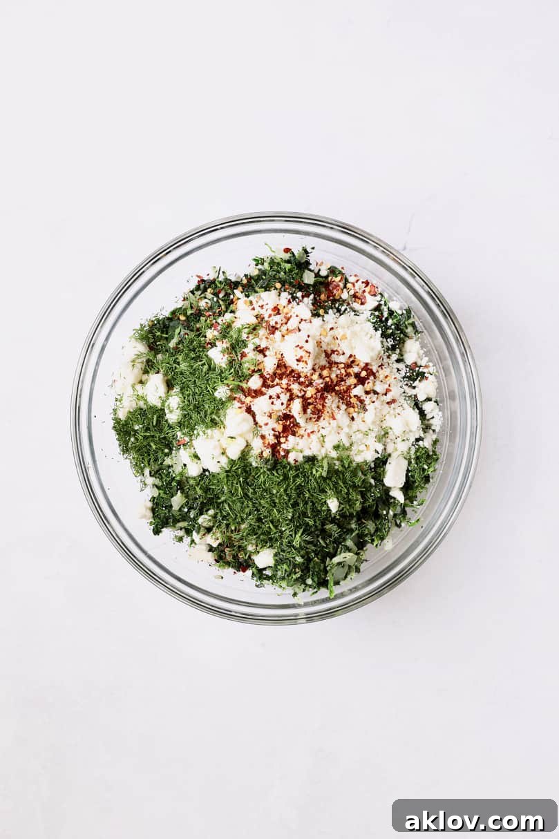 Skillet Spanakopita with Spinach and Feta 7 Photo of all ingredients for spanakopita filling combined in a glass bowl, before mixing. This image shows the distinct elements of the savory filling.