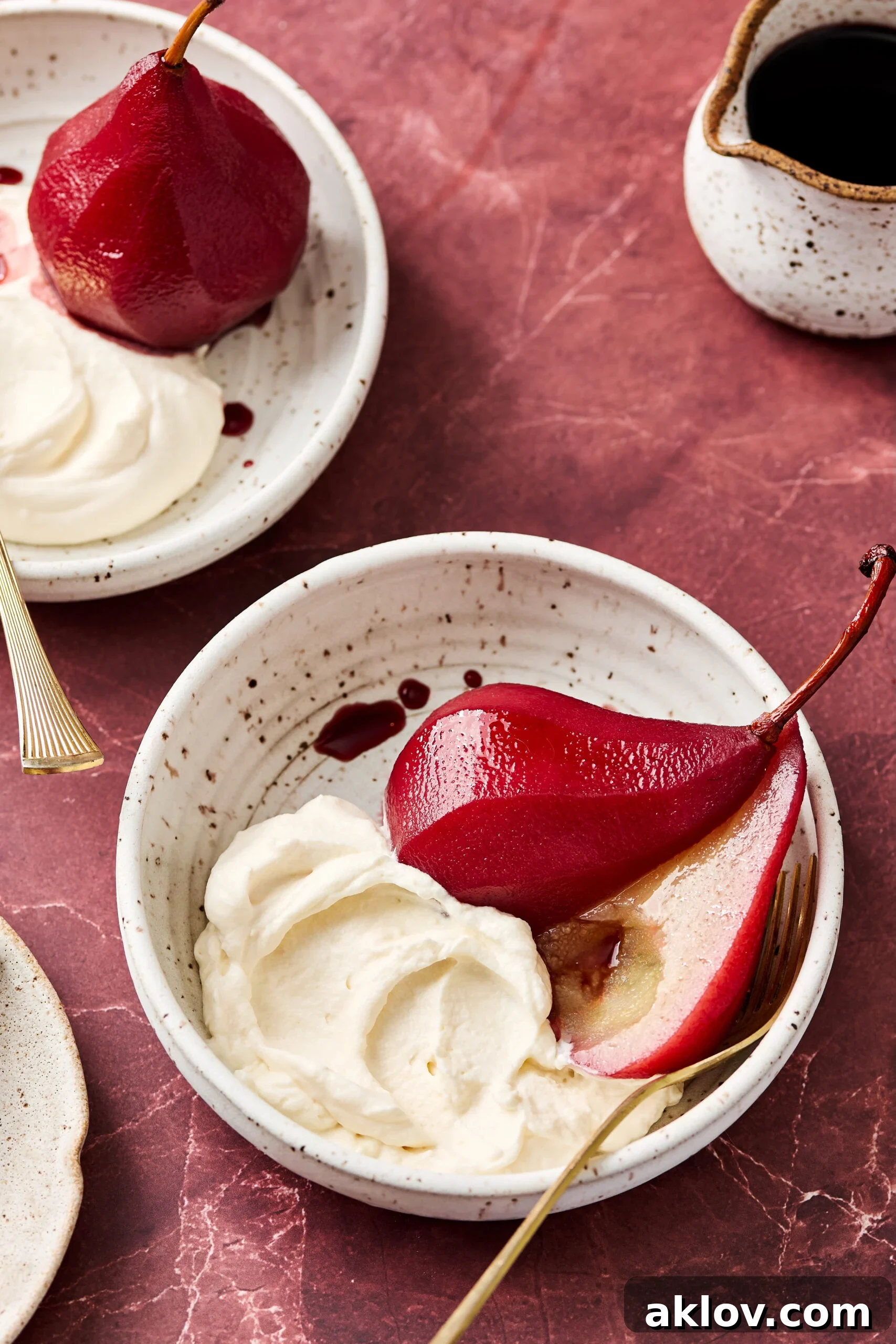 Poached pear sliced in half in a bowl with Mascarpone Whipped Cream.
