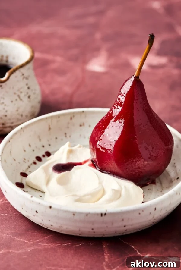 Poached pear sliced in half in bowl with Mascarpone Whipped Cream.