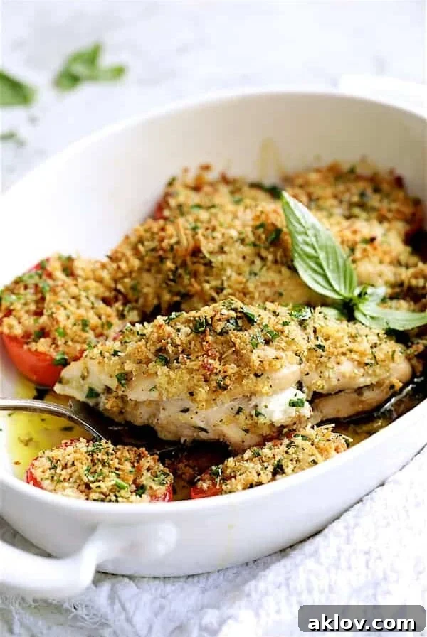 Pesto and Goat Cheese-Stuffed Chicken with Roma Tomatoes - Finished dish being served with serving fork from white baking dish