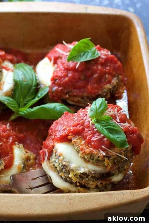 Eggplant Parmesan Stacks in earthenware baking dish being lifted out with fork.
