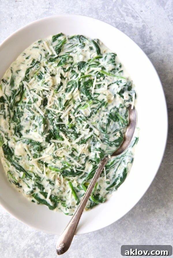 Steakhouse Creamed Spinach in white oval bowl with serving spoon.