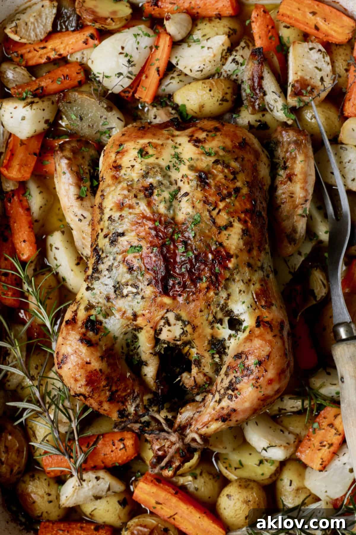 Close-up photo of carved Garlic Herb Butter Roast Chicken with Root Vegetables, showing tender meat, vibrant caramelized vegetables, and pan juices.