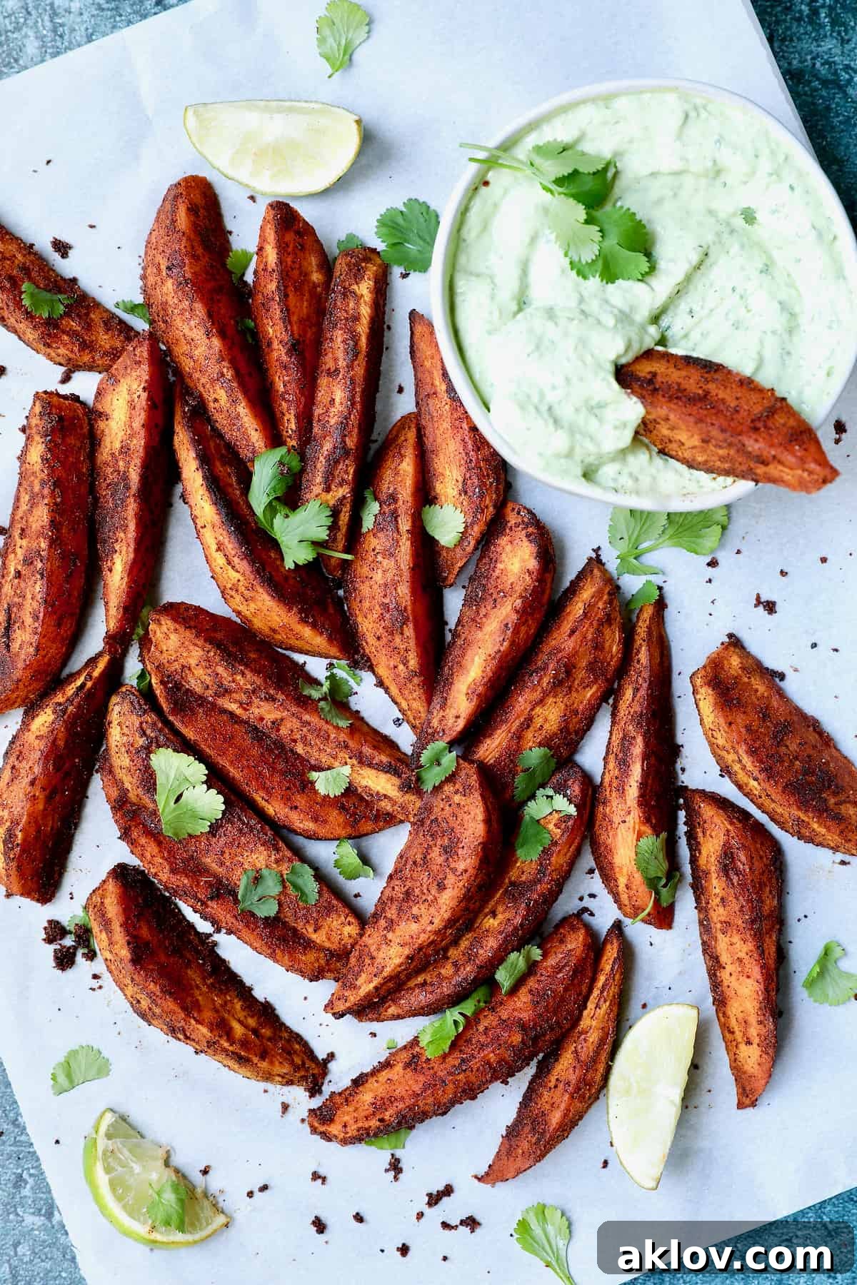 Southwestern Sweet Potato Wedges with Avocado - Cilantro Sour Cream with lime wedges, garnished with fresh cilantro.