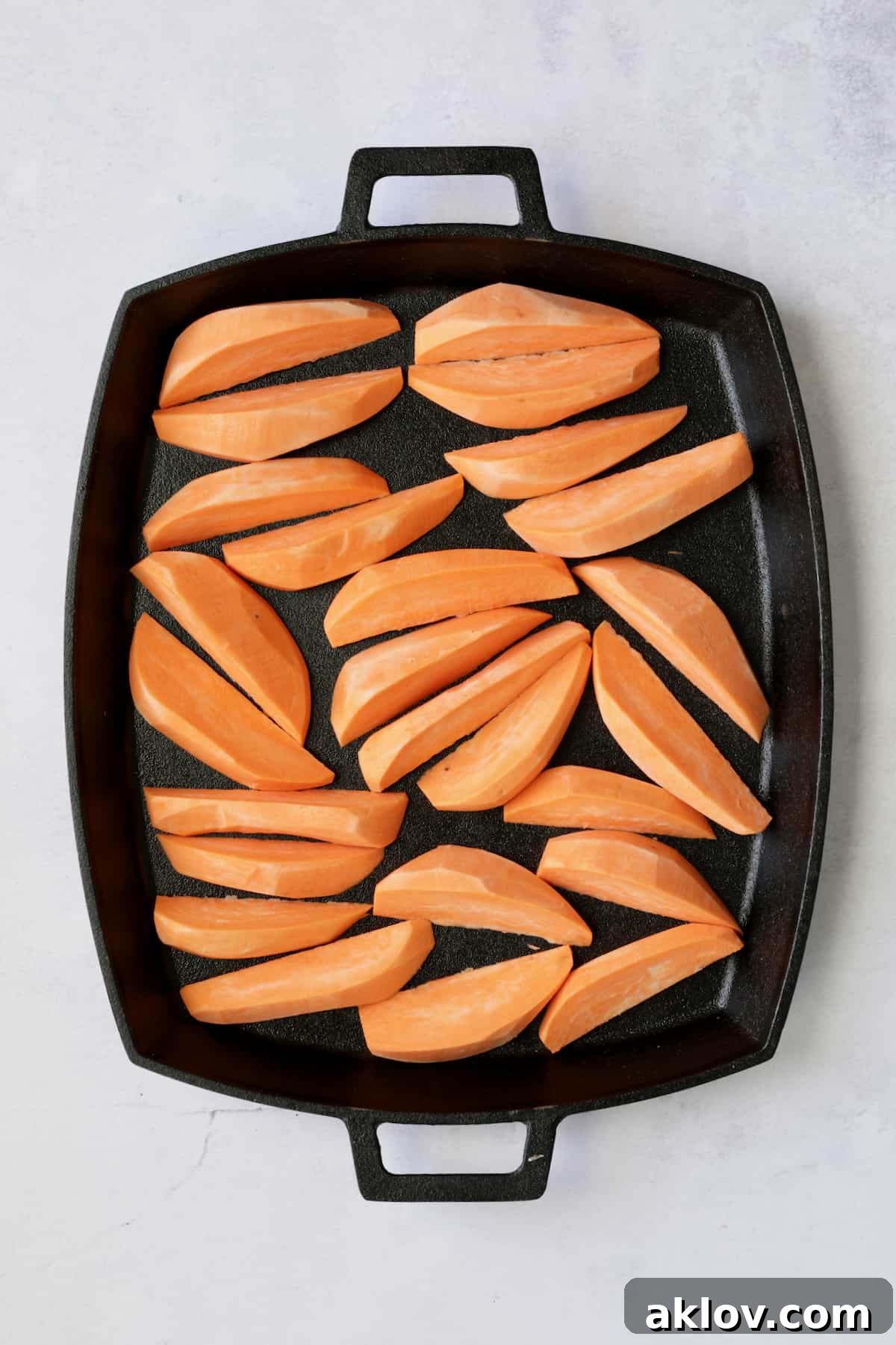 Sweet potato wedges on cast iron pan before being roasted.