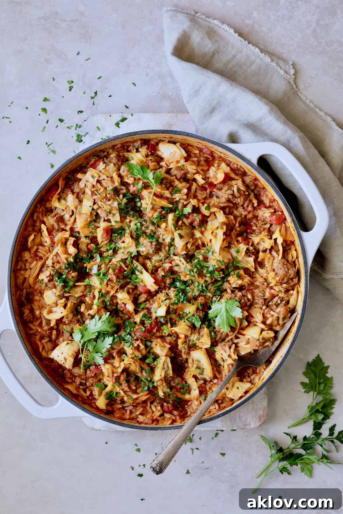 A vibrant photo of Unstuffed Chorizo Cabbage Roll Skillet served on a beige surface, garnished with fresh parsley.