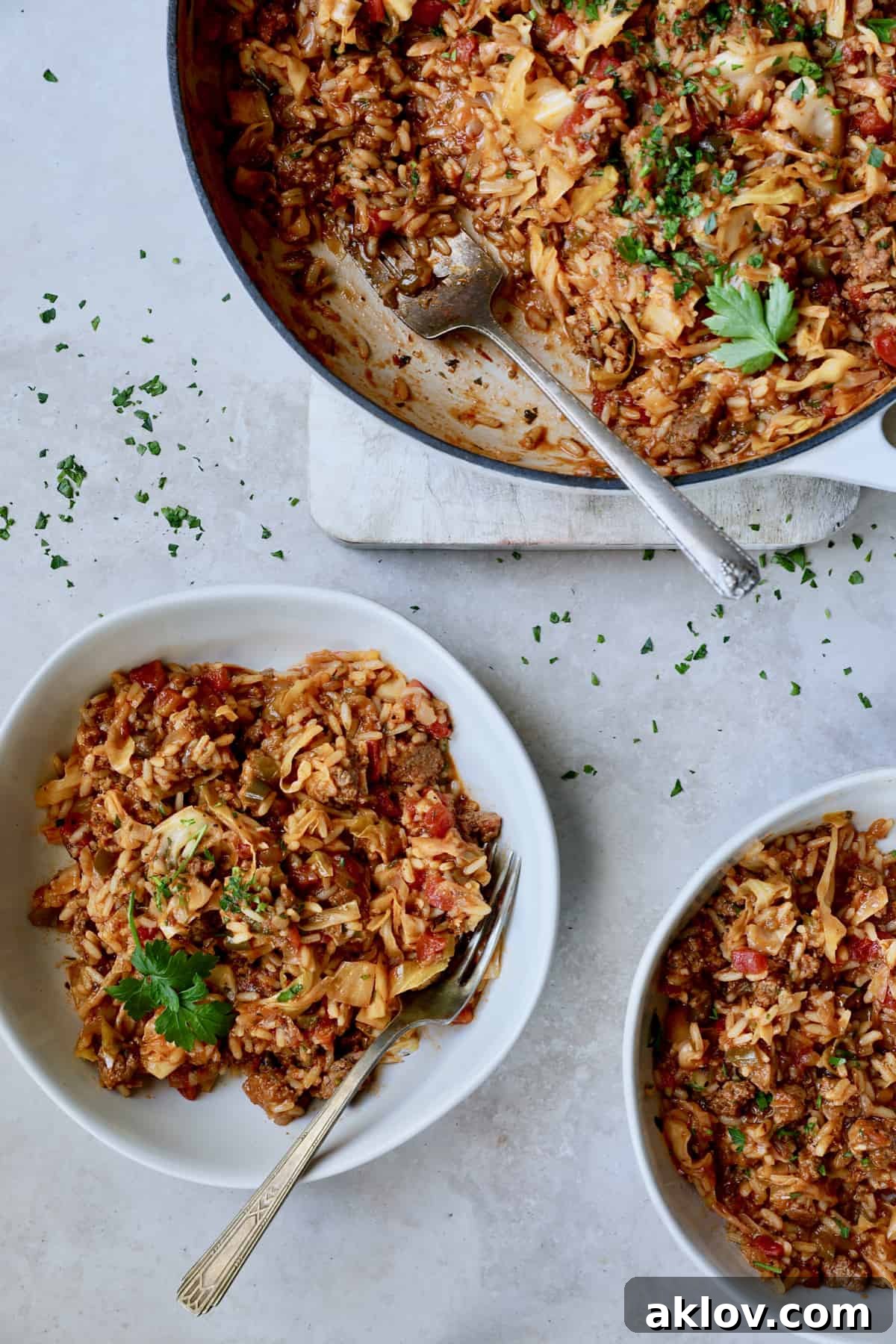 Multiple servings of Unstuffed Chorizo Cabbage Roll Skillet in individual bowls, with more visible in the white enamel skillet.