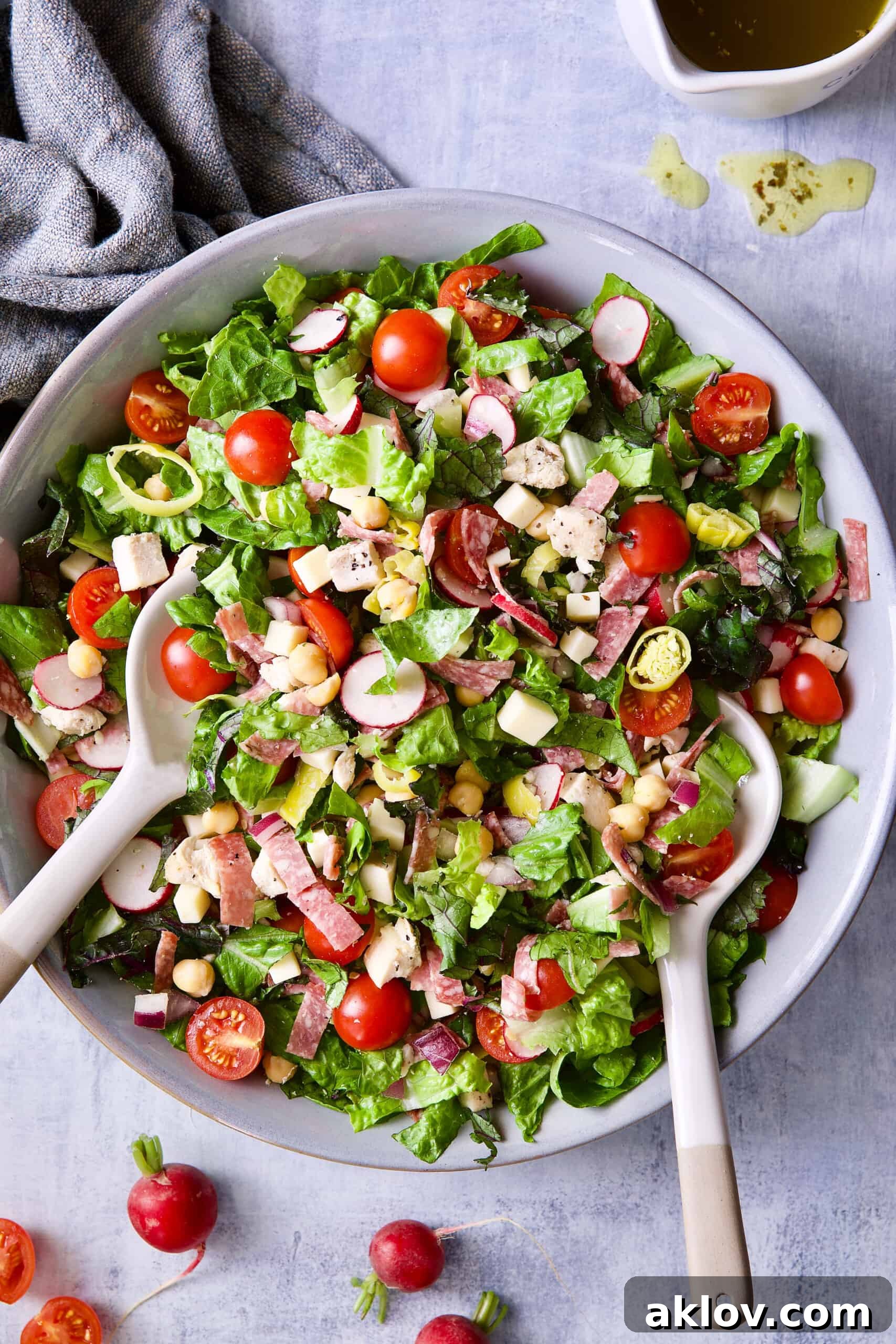 A large gray bowl filled with Italian Chopped Salad with Chicken, accompanied by serving utensils.