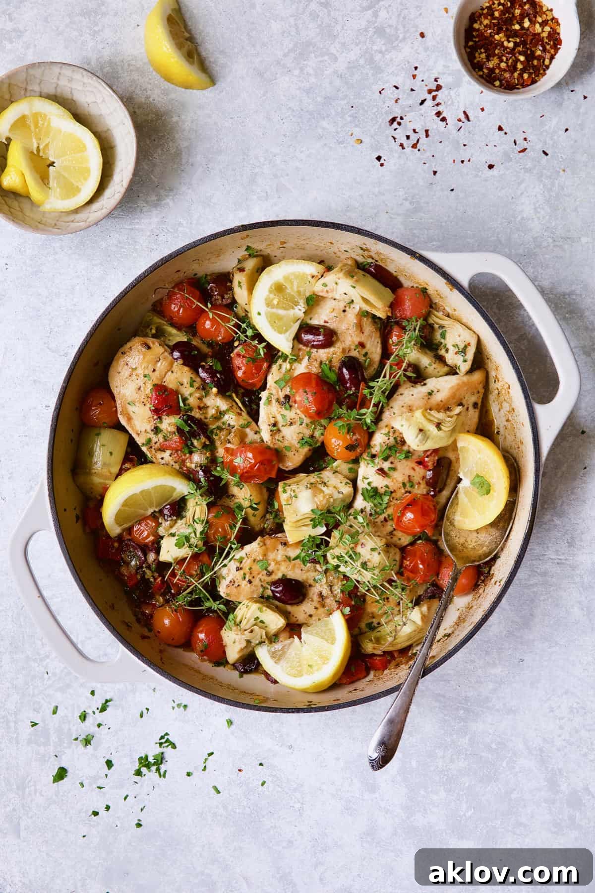 Easy Skillet Mediterranean Chicken in white enamel skillet garnished with lemon wedges and fresh thyme.