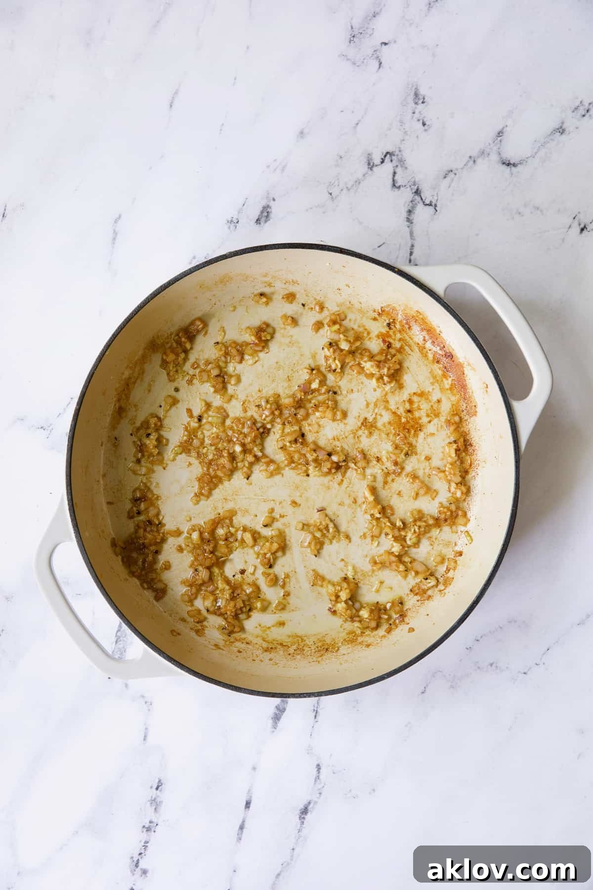 Browned cooked shallots in white enamel cast iron skillet.