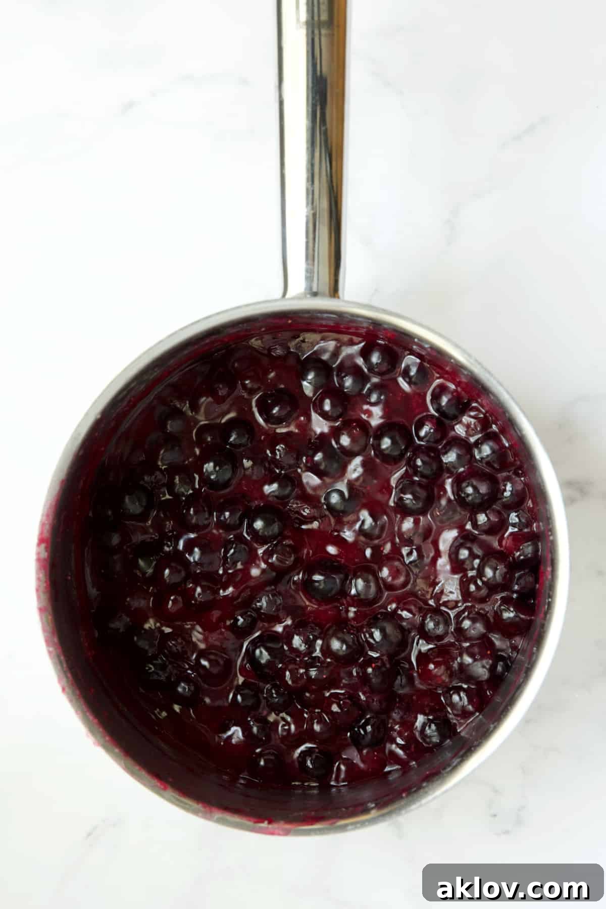 Process photo of blueberries in stainless steel saucepan.