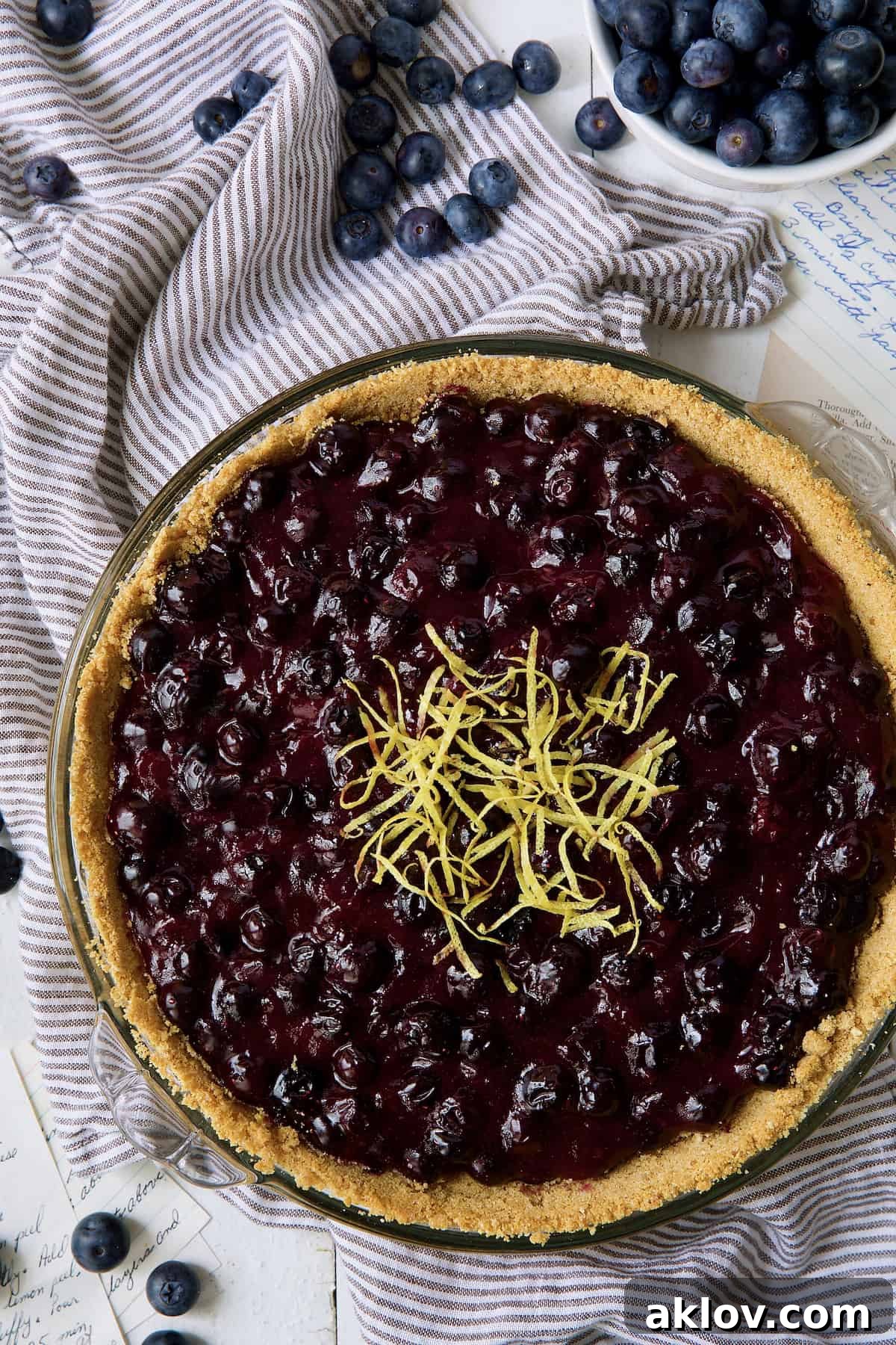 Photo of a whole Blueberry Cream Cheese Pie on blue-striped towel.