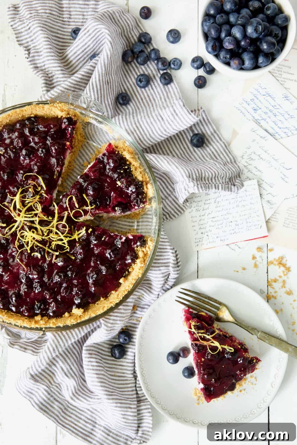 Photo of Blueberry Cream Cheese Pie on white background with pieces cut and one on white plate.