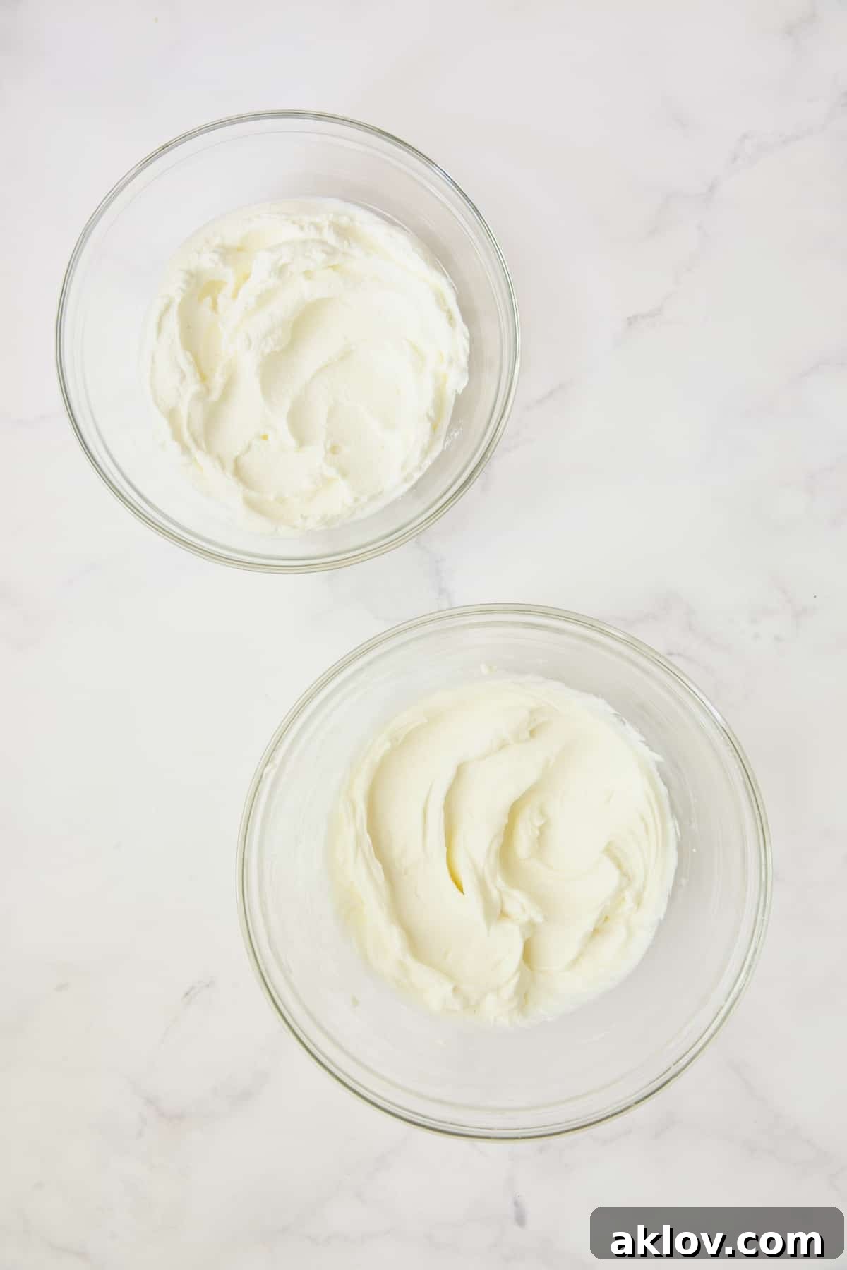 Process photo of whipped cream and cream cheese in glass bowls.