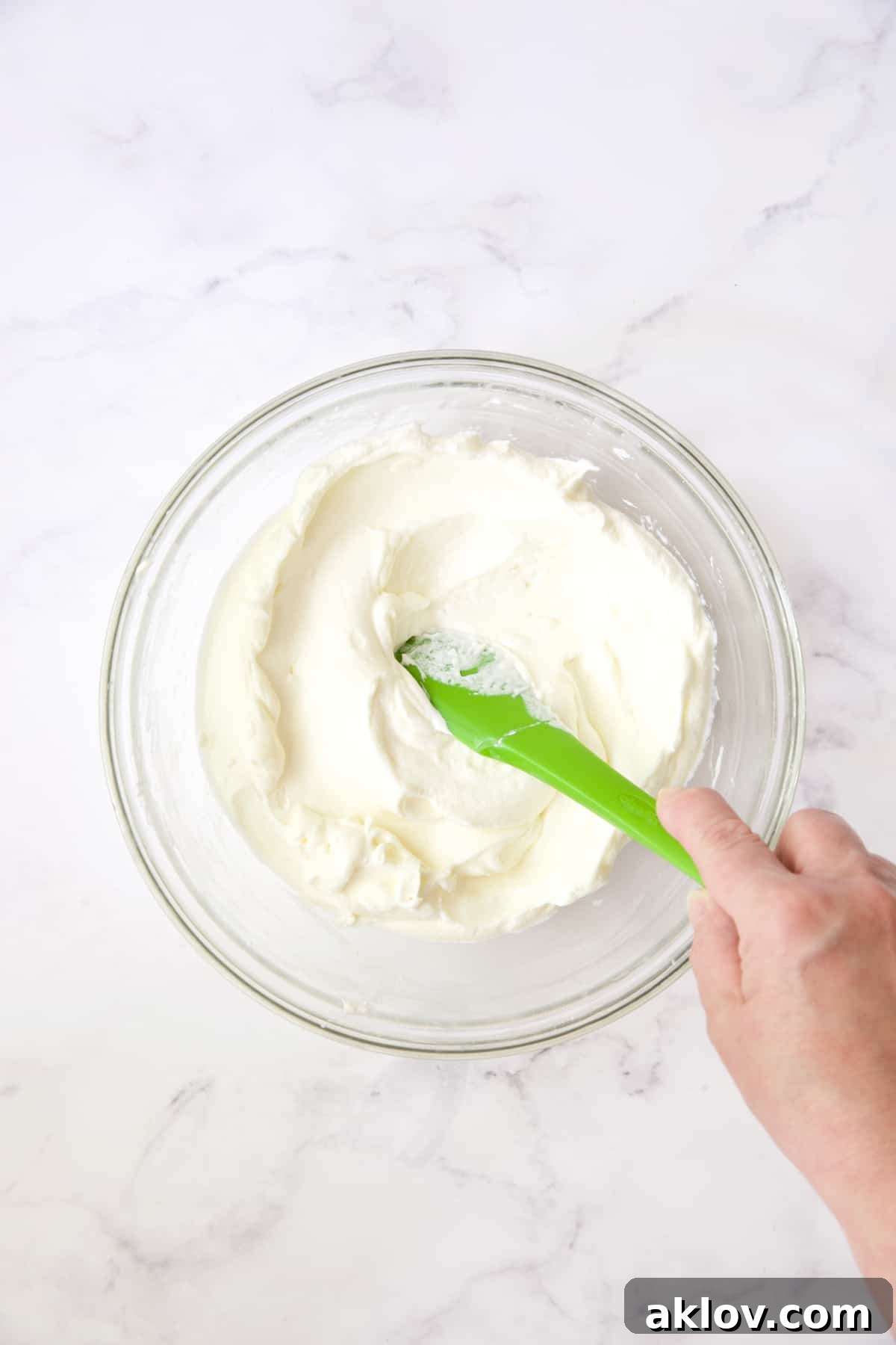 Process photo of cream cheese and whipped cream being folded together.