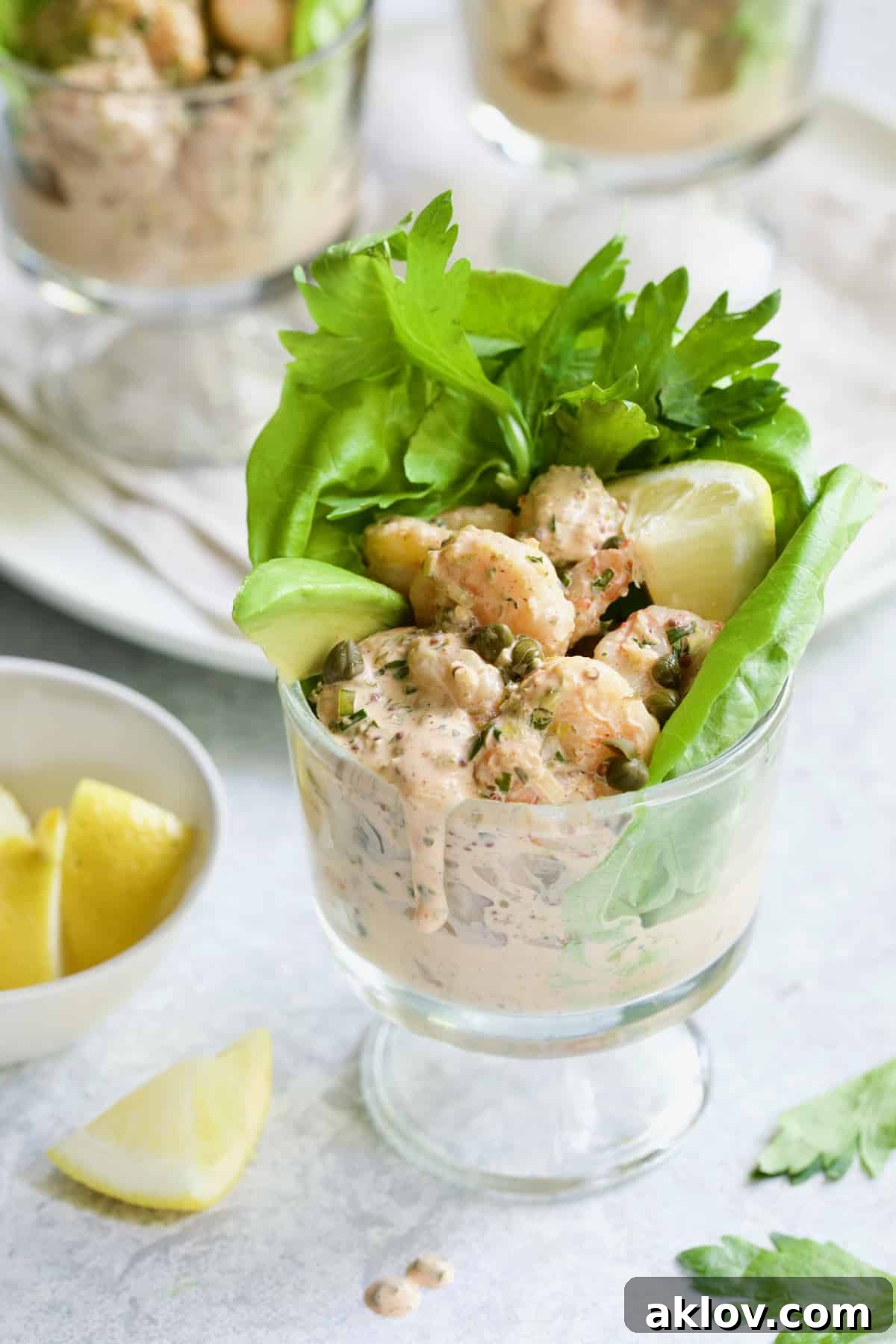 Sriracha Shrimp Remoulade Cocktail in footed glass with sauce dripping down the side.